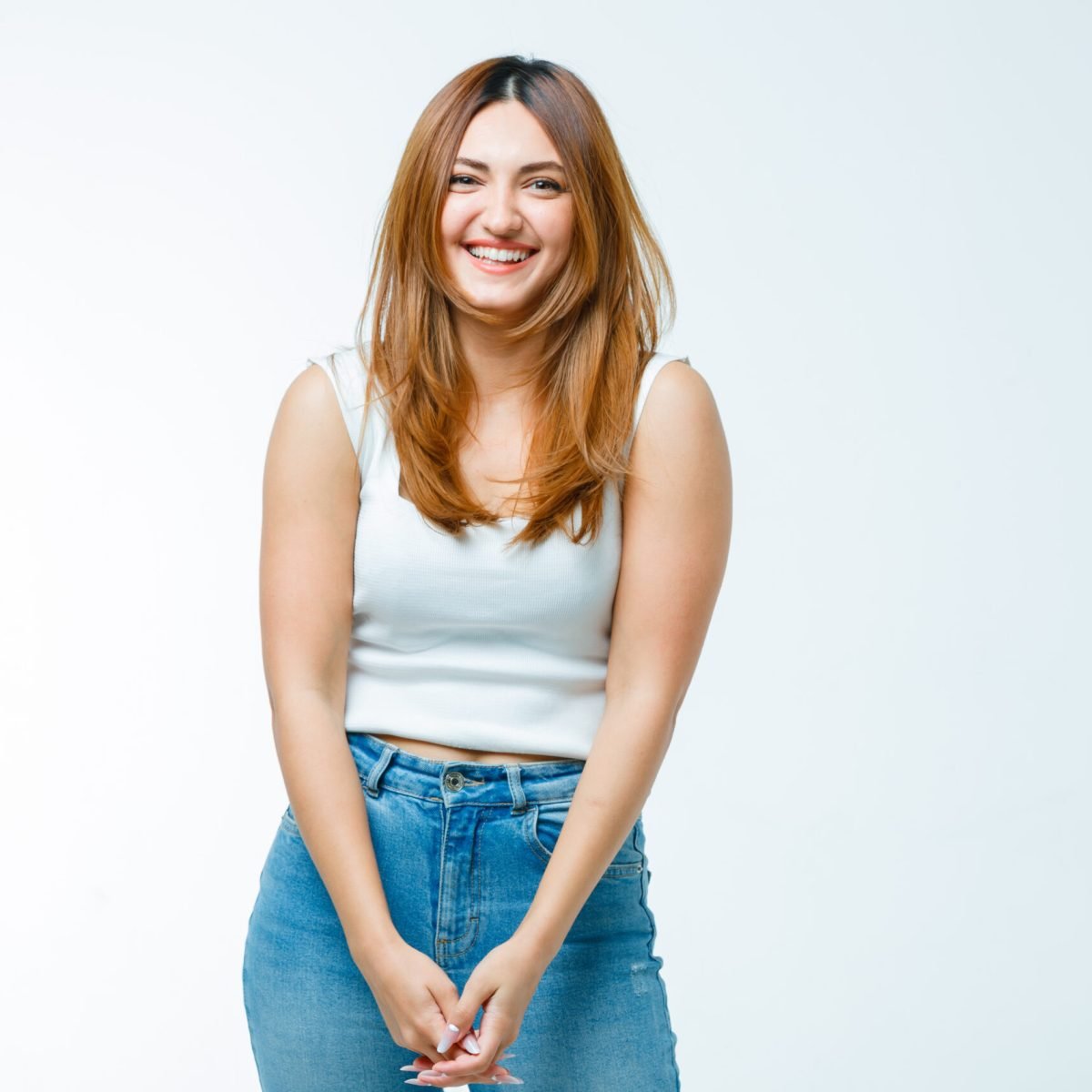 young lady in singlet, jeans smiling at camera and looking positive , front view.